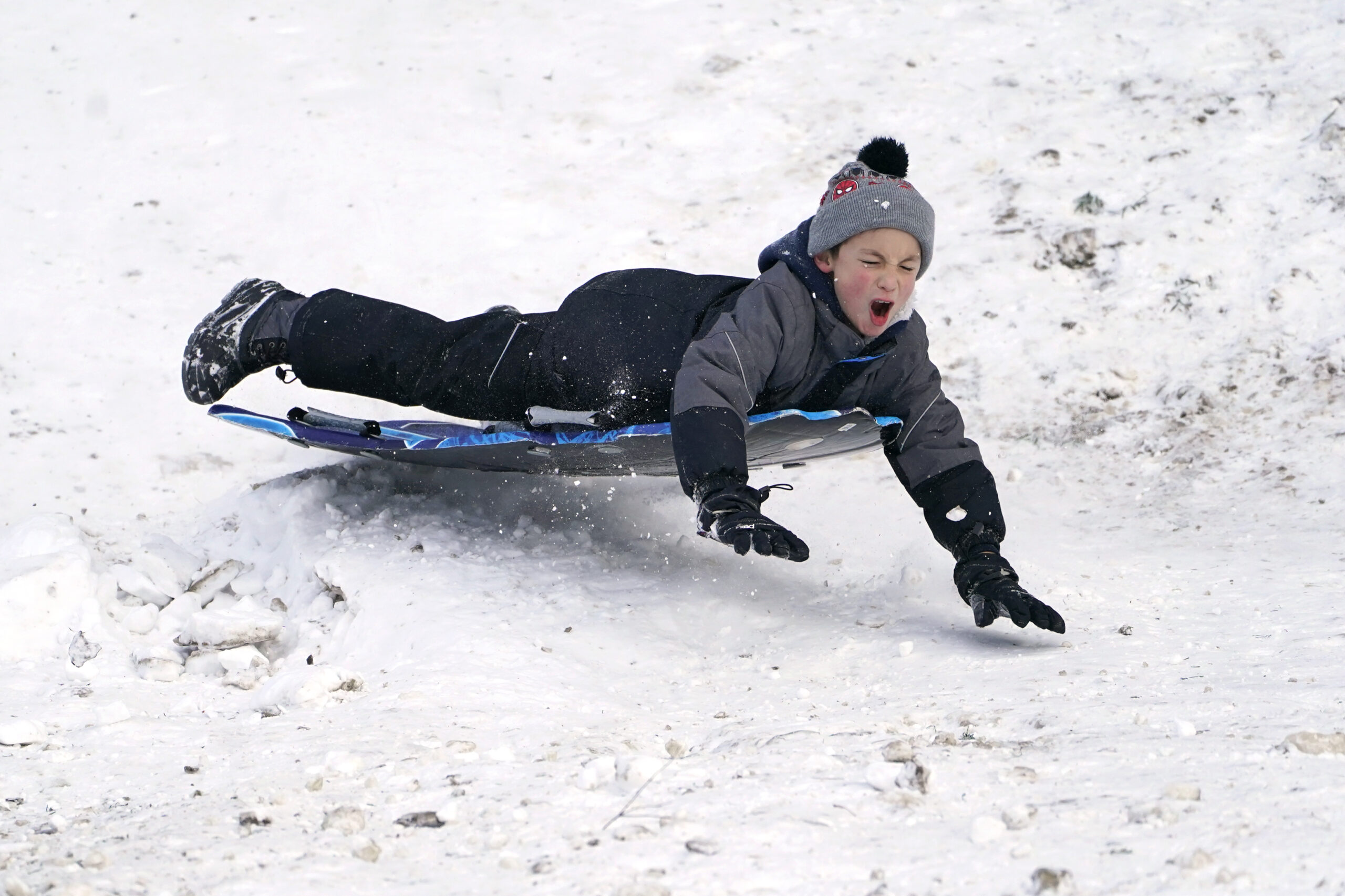 Titus Gonzalez goes airborne after hitting a bump while sledding where nearly a foot of snow fell over the weekend, Monday, Dec. 27, 2021, in a city park in Bellingham, Wash. Sunday's snow showers blew into the Pacific Northwest from the Gulf of Alaska, dumping up to 6 inches across the Seattle area. More than a foot was reported near Port Angeles across the Puget Sound on the Olympic Peninsula. (AP Photo/Elaine Thompson)