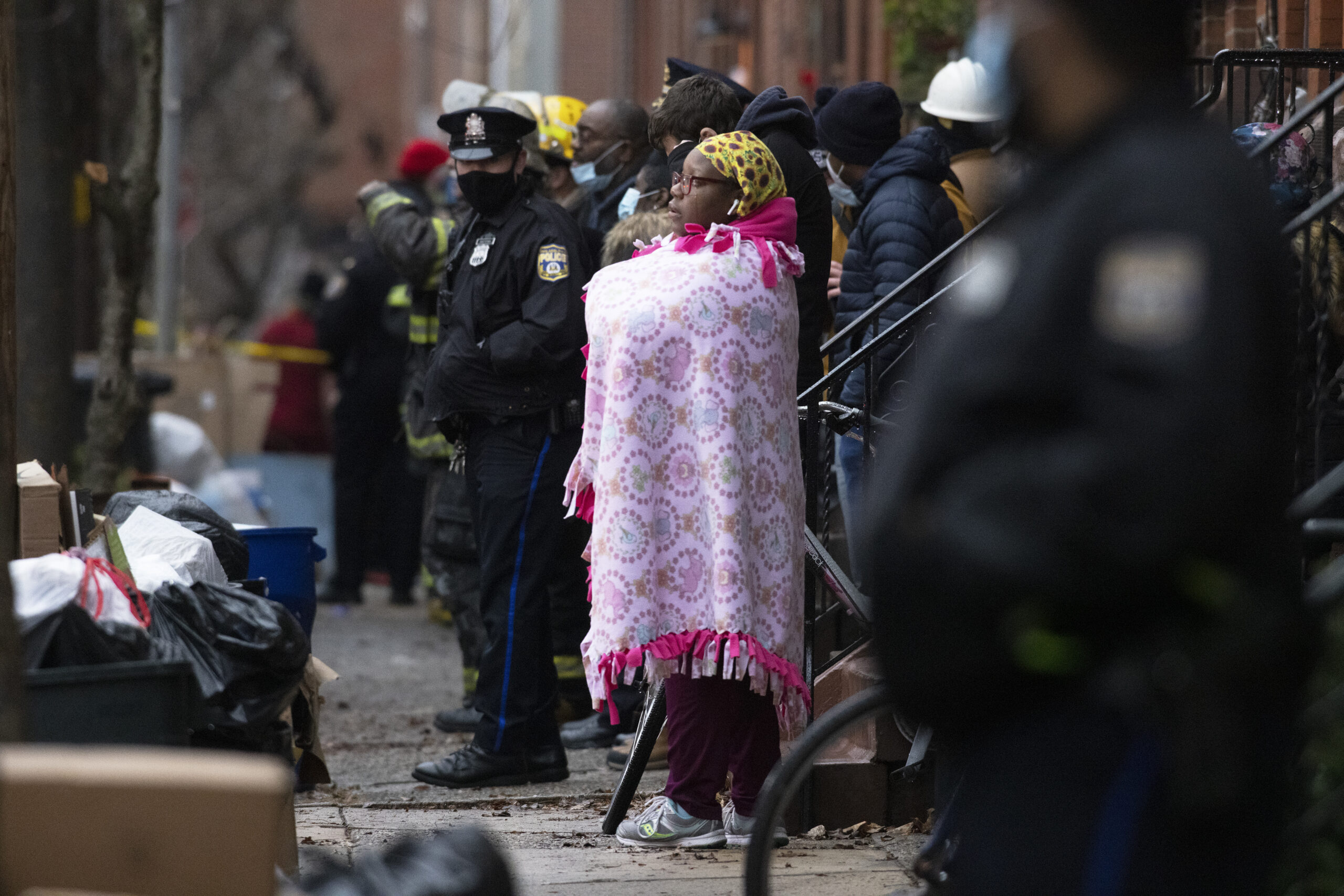 Bystanders watch as the Philadelphia fire department works at the scene of a deadly row house fire in Philadelphia on Wednesday, Jan. 5, 2022. Firefighters and police responded to the fatal fire at a three-story rowhouse in the city's Fairmount neighborhood around 6:40 a.m. and found flames coming from the second-floor windows, fire officials said. (Alejandro A. Alvarez/The Philadelphia Inquirer via AP)