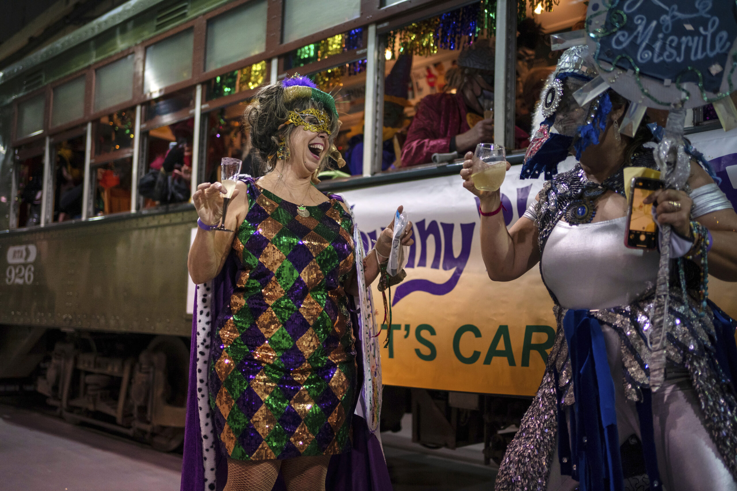 The Phunny Phorty Phellows (PPP) Queen Julie Holman, left, dances before hopping onto the street car to take their historic Twelfth Night ride to announce that Carnival has begun in New Orleans, Thursday, Jan. 6, 2022. The Phellows are a Mardi Gras organization that first took to the streets in 1878 and ceased parading in 1898. The group was revived in 1981. They were known for their satirical parades and today's krewe members' costumes often reflect current events. (AP Photo/Kathleen Flynn)