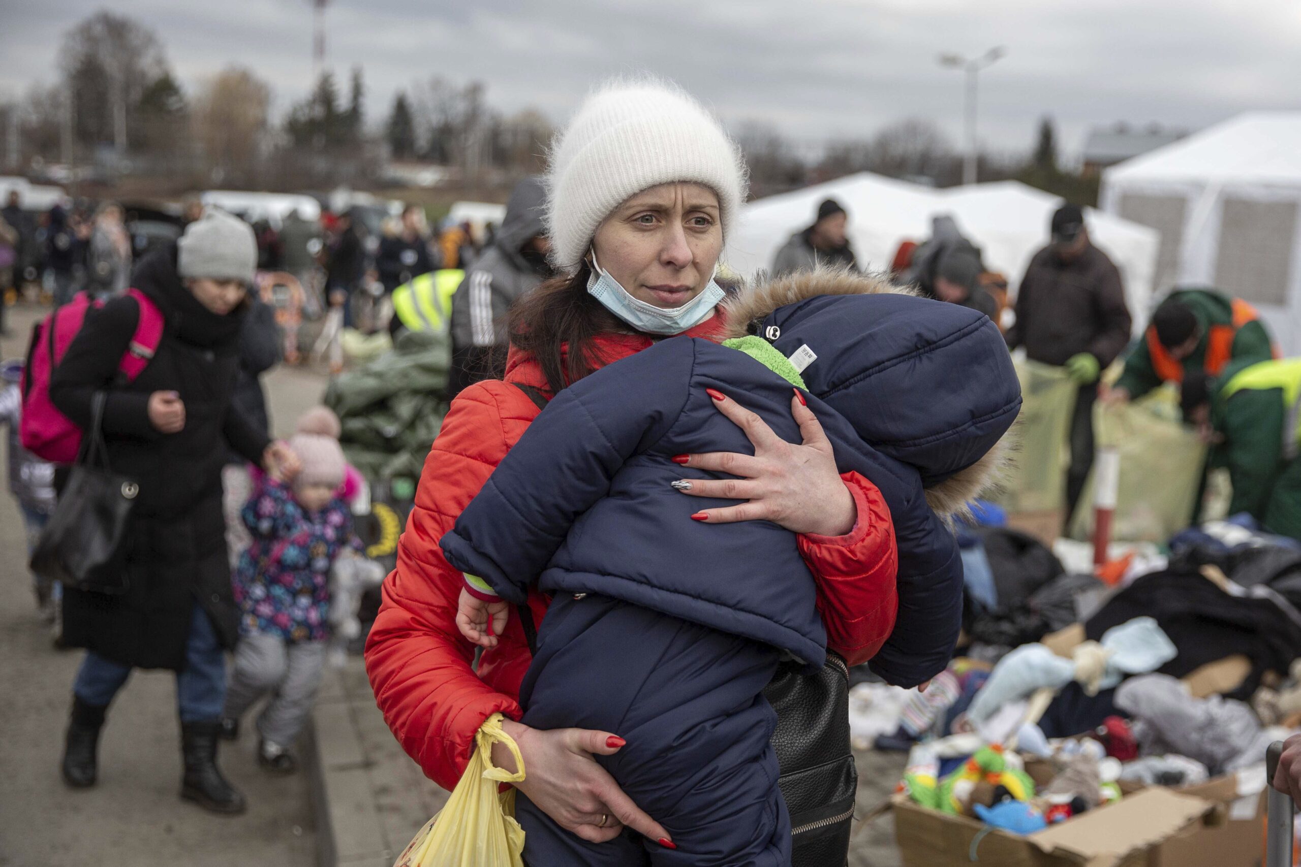 A woman carries her child as she arrives at the Medyka border crossing after fleeing from the Ukraine, in Poland, Monday, Feb. 28, 2022. The head of the United Nations refugee agency says more than a half a million people had fled Ukraine since Russia’s invasion on Thursday. (AP Photo/Visar Kryeziu)