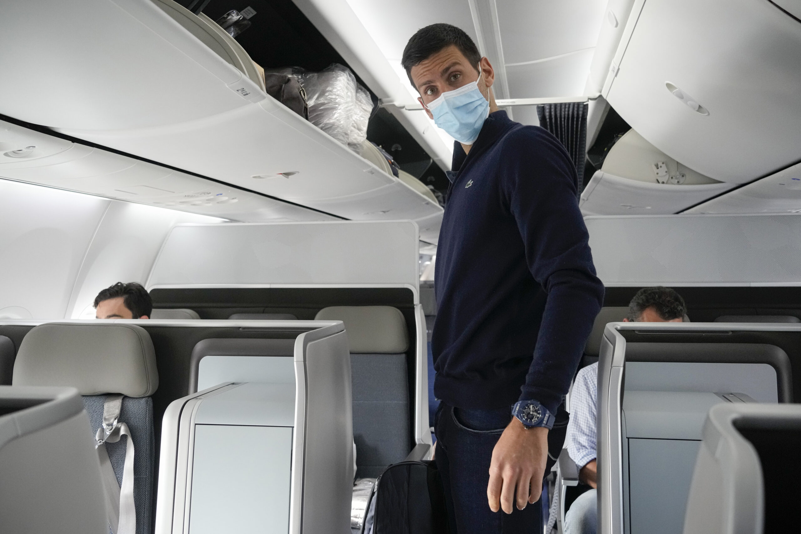 FILE - Novak Djokovic prepares to take his seat on a plane to Belgrade, in Dubai, United Arab Emirates, Monday, Jan. 17, 2022. Djokovic was deported from Australia after losing a bid to stay in the country to defend his Australian Open title despite not being vaccinated against COVID-19. Prime Minister Scott Morrison said on Monday, Feb. 7, 2022, that the border would reopen to all vaccinated visas holders from Feb. 21. (AP Photo/Darko Bandic, FILE)