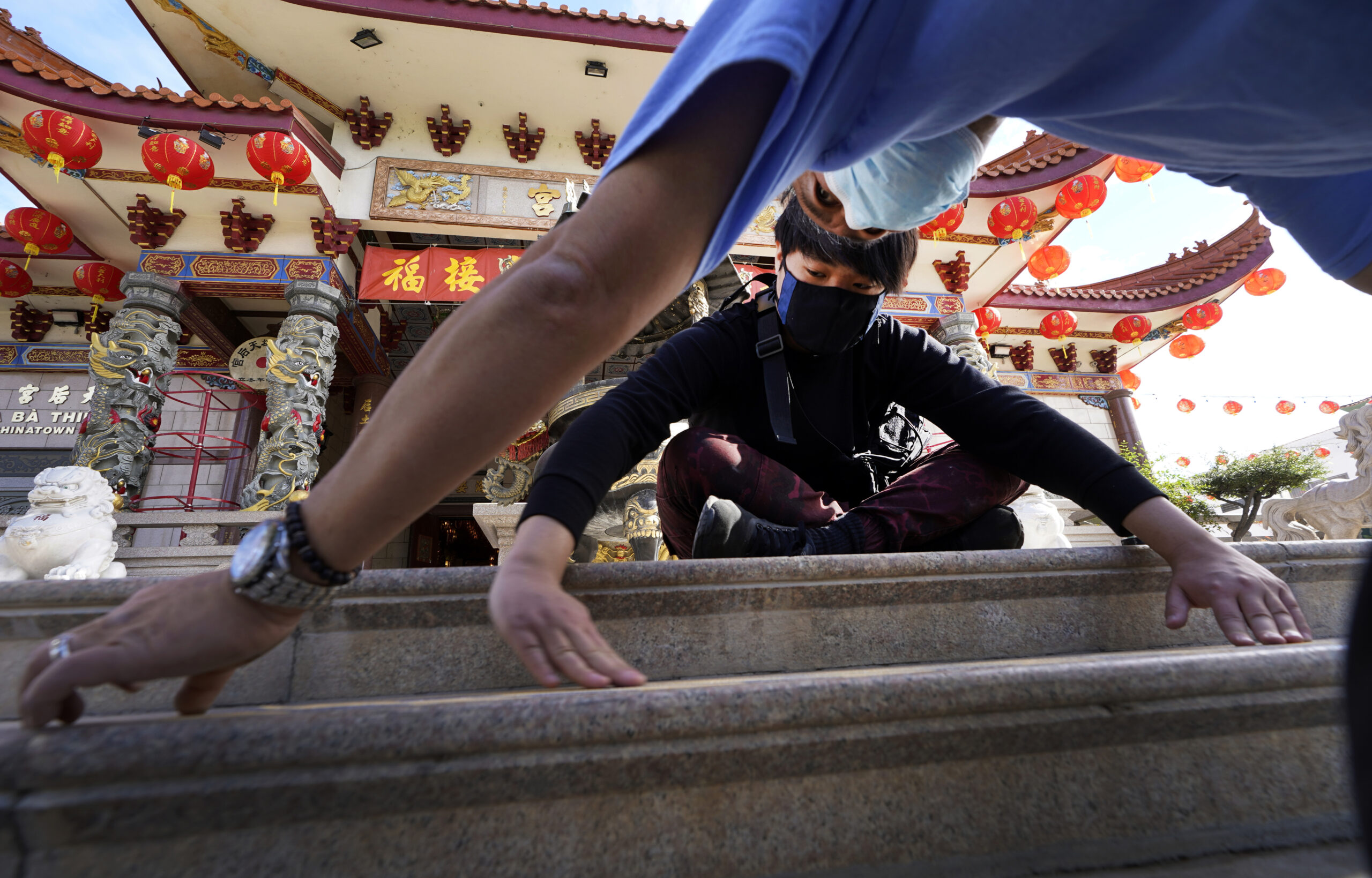 Volunteers, Alex Koi, foreground, and his son Lipsun Koi, 20, help install anti-slip tape on the front steps of the Thien Hau Temple ahead of the crowds expected for the Lunar New Year of the Tiger celebrations in the Chinatown district of Los Angeles, Friday, Jan. 28, 2022. The Lunar New Year of the Tiger celebrations will occur on Feb. 1, amid warnings against travel and large gatherings due to COVID-19. (AP Photo/Damian Dovarganes)