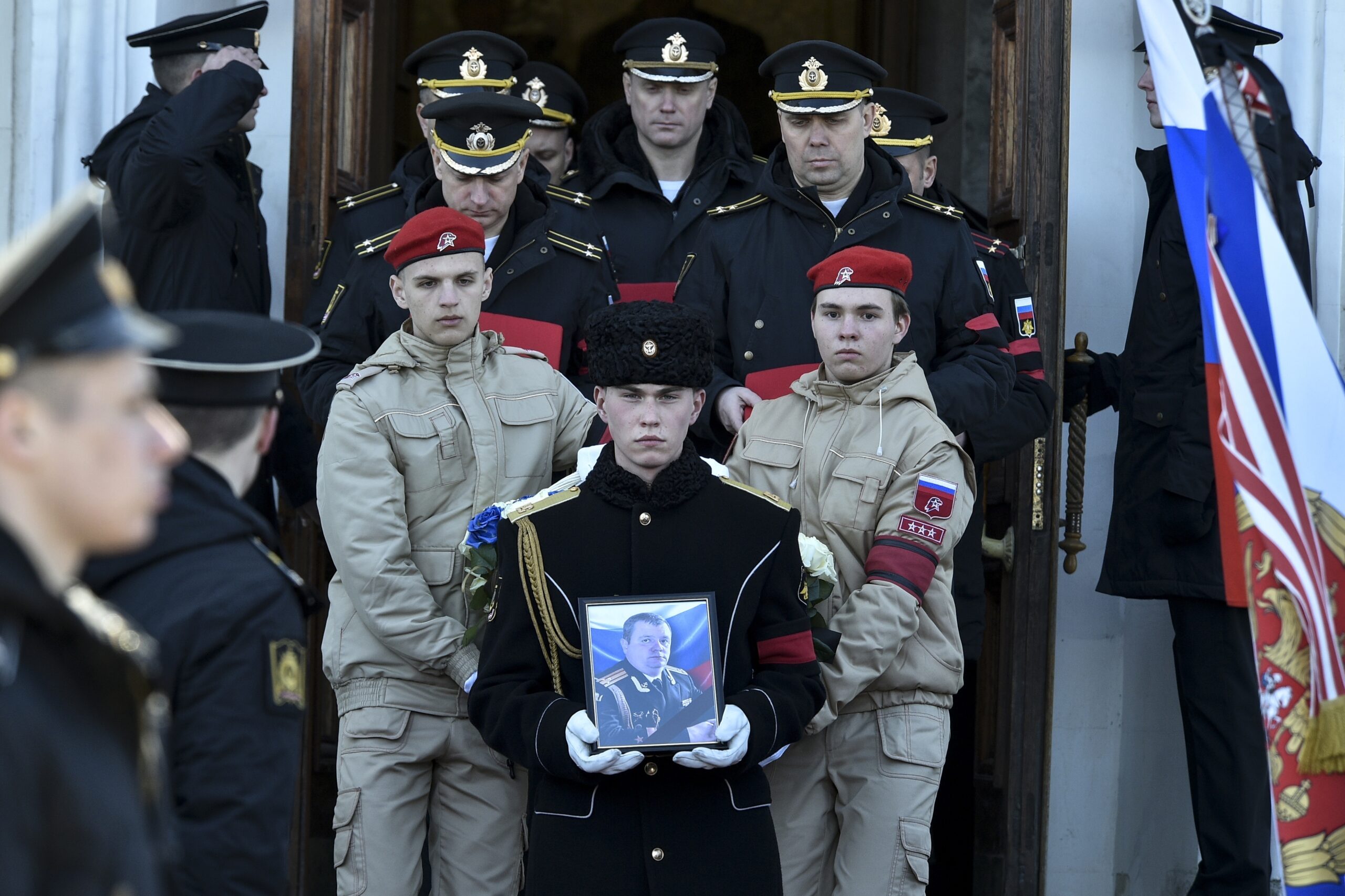 A serviceman carries the photo of Capt. Andrei Paliy, a deputy commander of Russia's Black Sea Fleet, during a farewell ceremony in Sevastopol, Crimea, Wednesday, March 23, 2022. Paliy was killed in action during fighting with Ukrainian forces in the Sea of Azov port of Mariupol. (AP Photo)