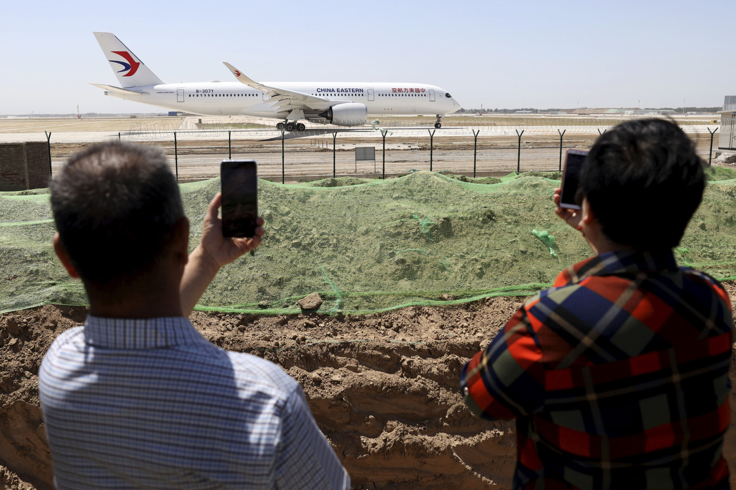 FILE - Residents watch as a China Eastern passenger jet prepares to take off on a test flight from the new Beijing Daxing International Airport on Monday, May 13, 2019. State media are reporting a Chinese airliner from China Eastern with 133 people on board crashed in the southern province of Guangxi on Monday, sparking a mountainside fire. (AP Photo/Ng Han Guan, File)