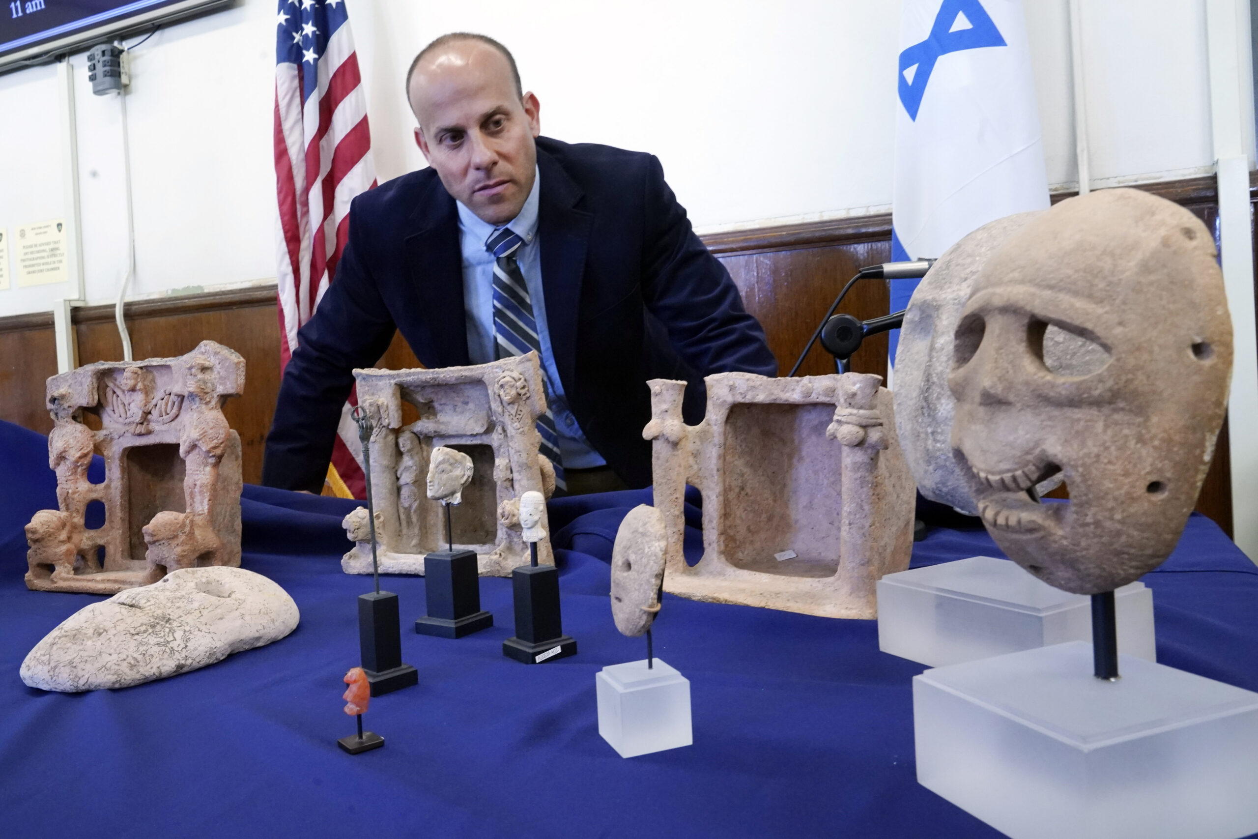 Dr. Etan Klein, Deputy Director of the Theft Prevention Unit, of Israel's Antiquities Authority, looks over looted antiquities worth $5-million, seized from billionaire hedge fund manager Michael Steinhardt, displayed in the offices of the Manhattan District Attorney, in New York, Tuesday, March 22, 2022. The 39 items being returned to Israel include two gold masks dating from about 5000 B.C. that are valued at $500,000, and a set of three death masks that date from 6000 to 7000 B.C. and are worth a total of $650,000, (AP Photo/Richard Drew)