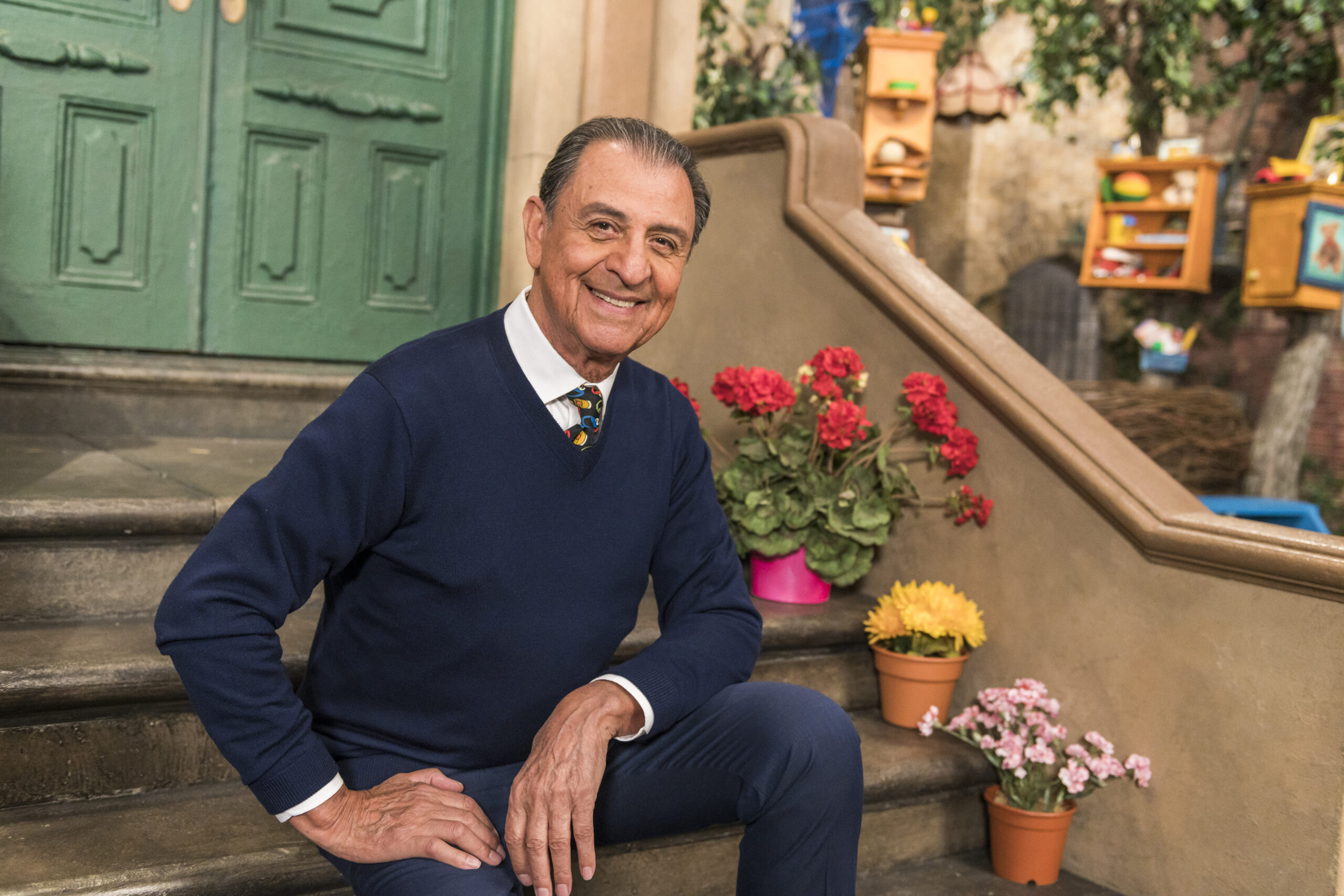 In this photo provided by Sesame Workshop, Emilio Delgado poses for a picture at Kaufman Astoria Studios while filming the 50th season of "Sesame Street," in October 2018. Delgado, the actor and singer who for 45 years was a warm and familiar presence in children's lives and a rare Latino face on American television as fix-it shop owner Luis on “Sesame Street,” died Thursday, March 10, 2022. He was 81. (Zach Hyman/Sesame Workshop via AP)