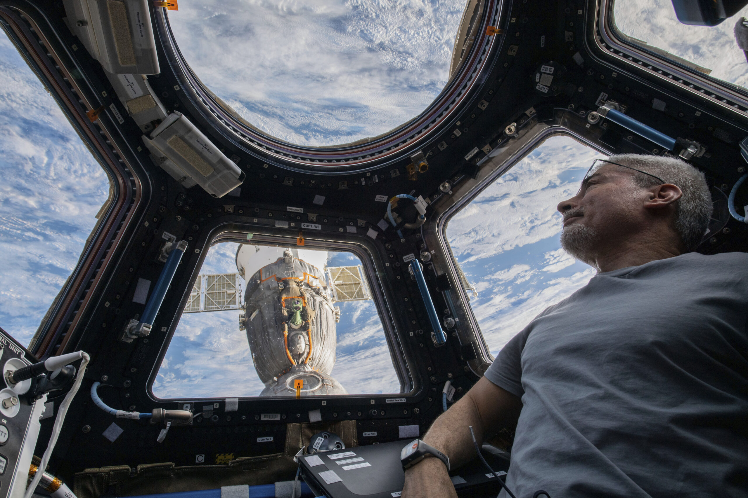 In this photo provided by NASA, U.S. astronaut and Expedition 66 Flight Engineer Mark Vande Hei peers at the Earth below from inside the seven-windowed cupola, the International Space Station's window to the world on Feb. 4, 2022. The Soyuz MS-19 crew ship is docked to the Rassvet module in the background. Vande Hei has made it through nearly a year in space, but in March 2022 faces what could be his trickiest assignment yet: riding a Russian capsule back to Earth in the midst of deepening tensions between the countries. (Kayla Barron/NASA via AP)