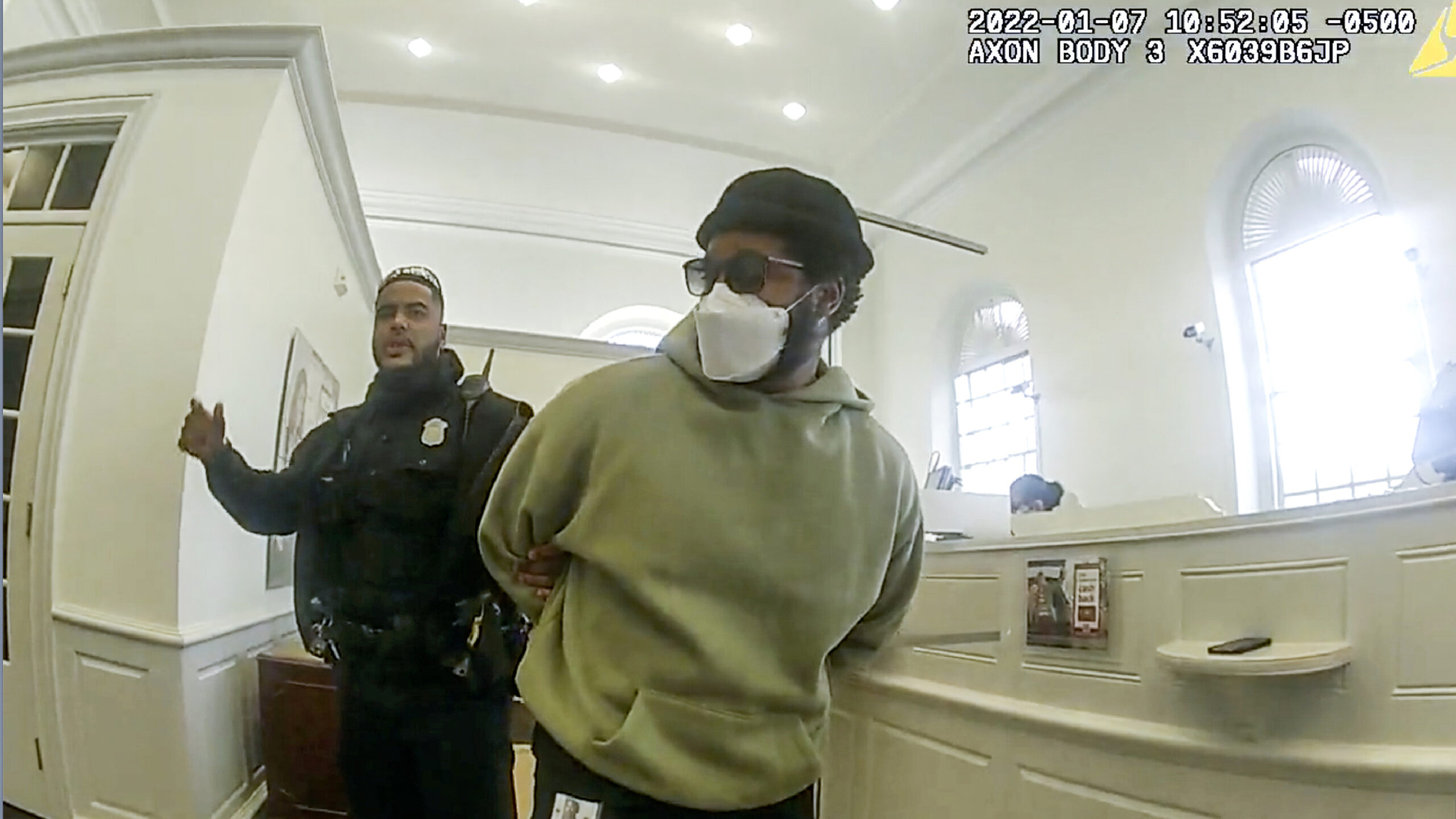 A police officer detains "Black Panther" director Ryan Coogler at a Bank of America branch in Atlanta, in this January 2022 image made from Atlanta Police video. Coogler was mistaken for a bank robber at the bank. (Atlanta Police Department via AP)