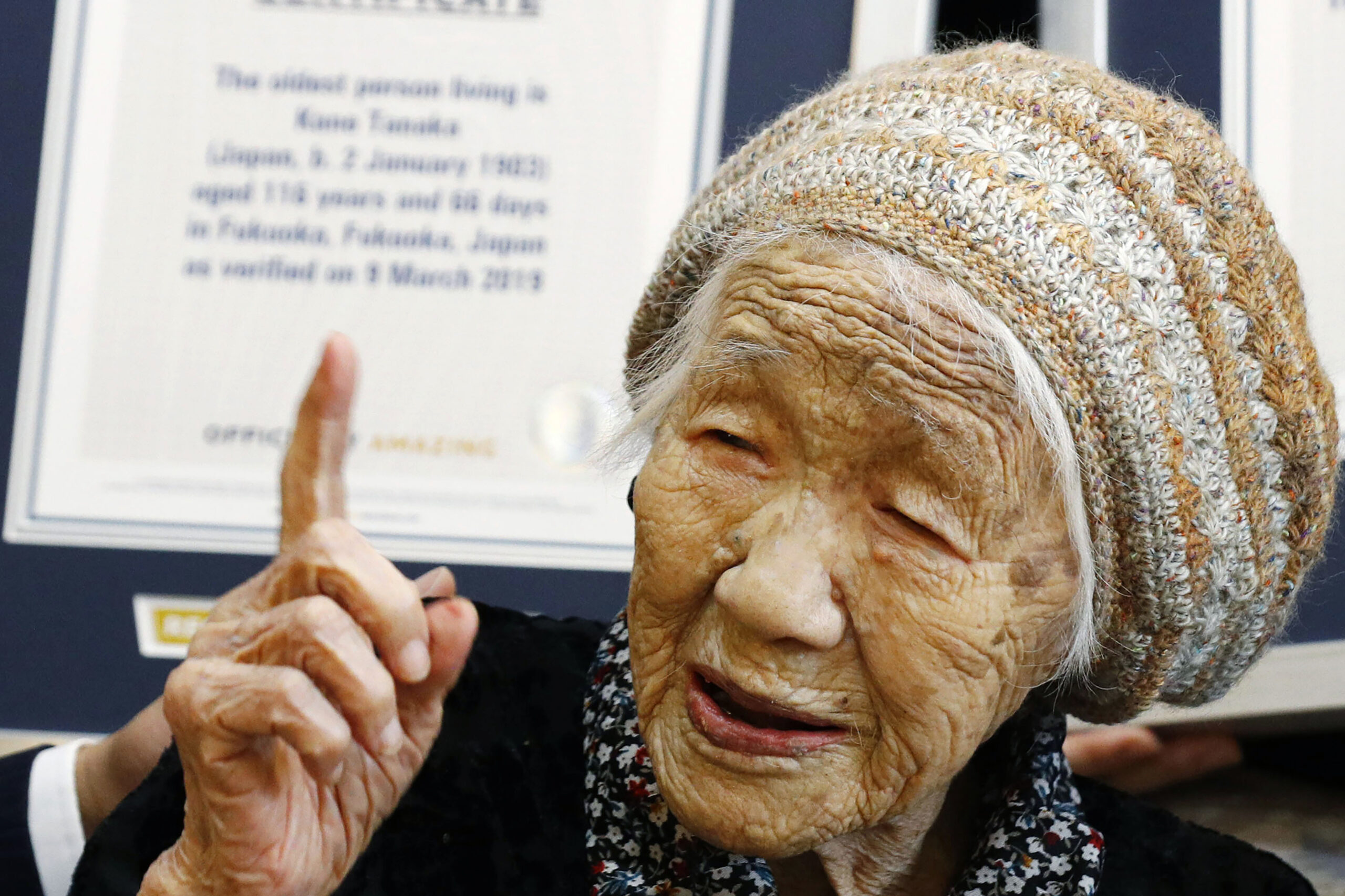 FILE - Kane Tanaka, then 116-years-old, reacts after receiving a Guinness World Records certificate, background, at a nursing home where she lives in Fukuoka, southwestern Japan on March 9, 2019. The Japanese woman recognized as the world’s oldest person Tanaka has died at age 119, just months short of her goal of reaching 120. (Takuto Kaneko/Kyodo News via AP, File)