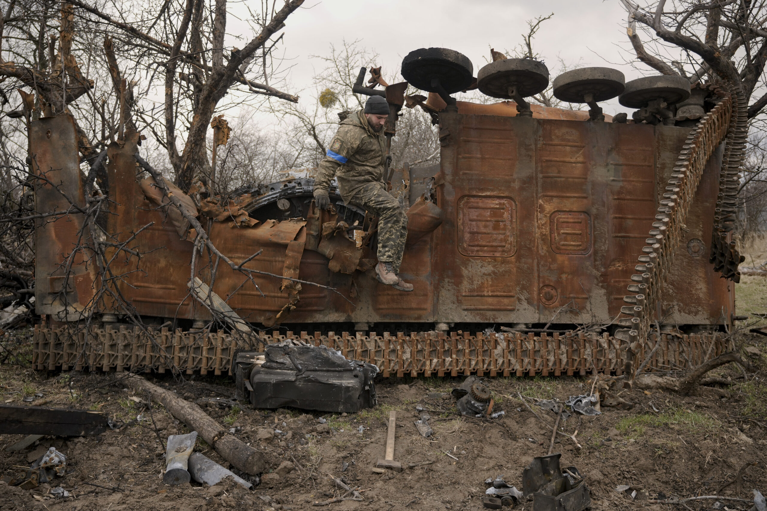 A Ukrainian serviceman jumps from a destroyed Russian fighting vehicle after collecting parts and ammunition in the village of Andriivka, Ukraine, heavily affected by fighting between Russian and Ukrainian forces, Wednesday, April 6, 2022. Several buildings in the village were reduced to mounds of bricks and corrugated metal and residents struggle without heat, electricity or cooking gas. (AP Photo/Vadim Ghirda)
