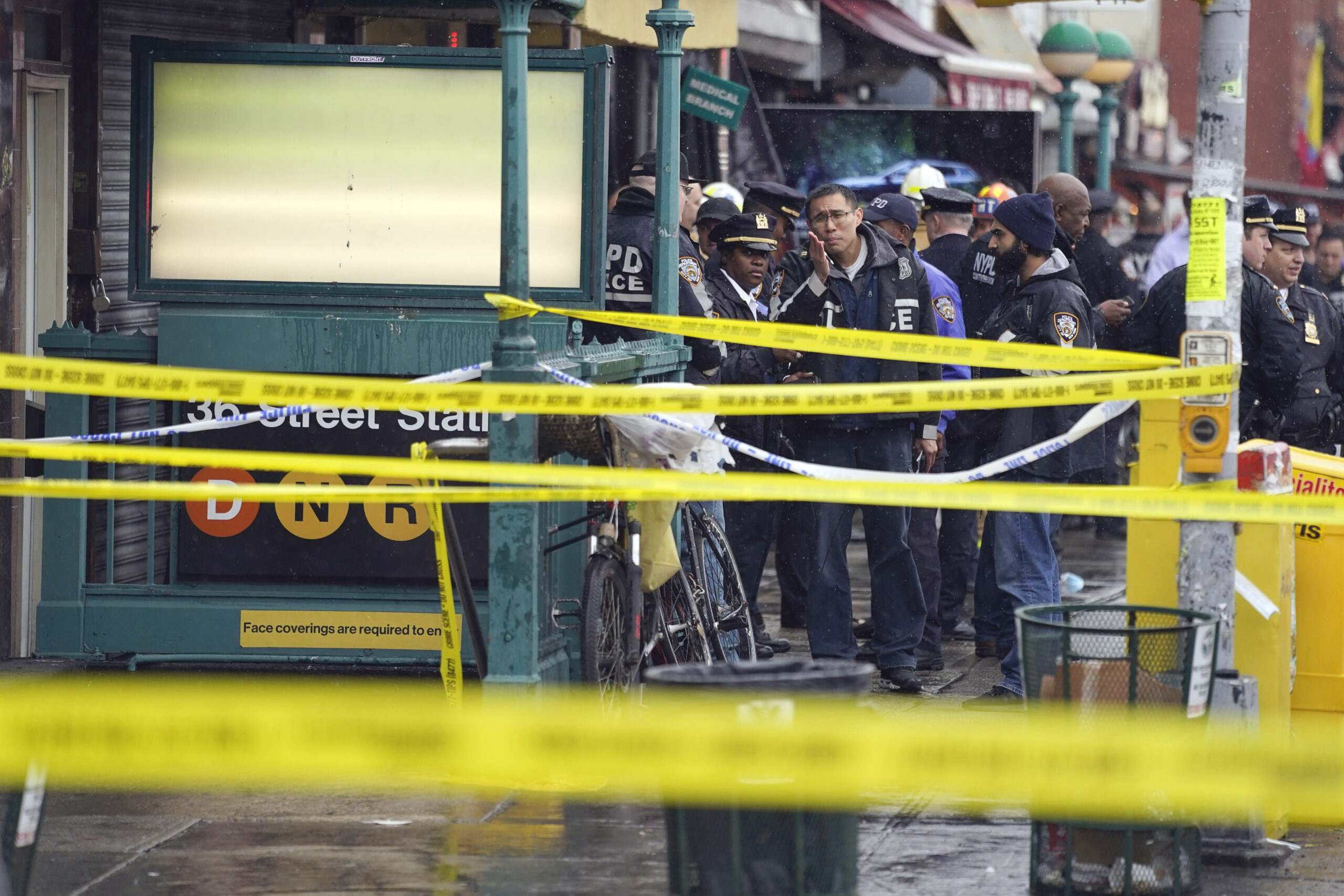 New York City Police Department personnel gather at the entrance to a subway stop in the Brooklyn borough of New York, Tuesday, April 12, 2022. Multiple people were shot and injured Tuesday at a subway station in New York City during a morning rush hour attack that left wounded commuters bleeding on a train platform. (AP Photo/John Minchillo)