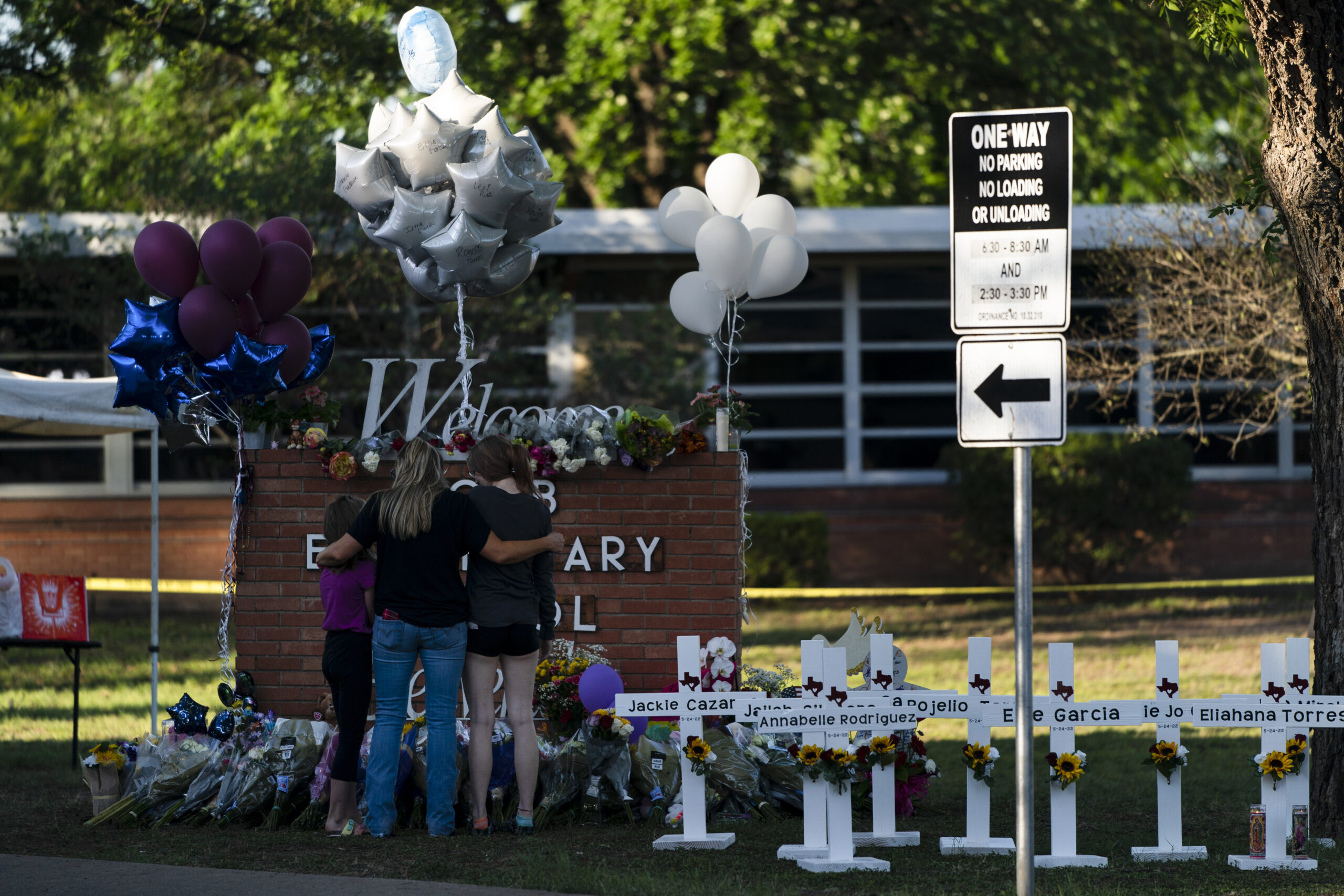 A family pays their respects next to crosses bearing the names of Tuesday's shooting victims at Robb Elementary School in Uvalde, Texas, Thursday, May 26, 2022. (AP Photo/Jae C. Hong)