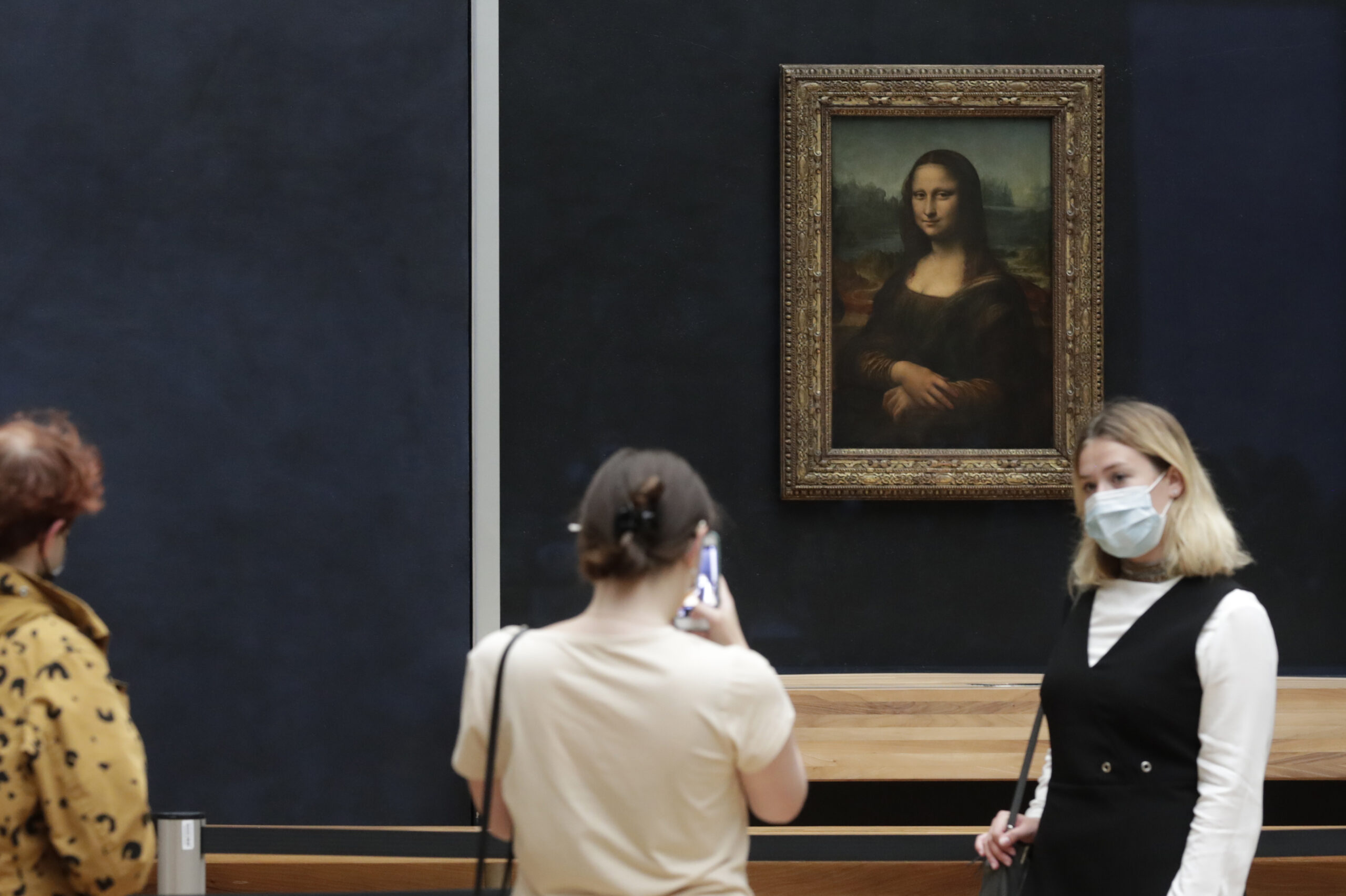 FILE - Visitors pose in front of Leonardo da Vinci's Mona Lisa in the Louvre museum, Wednesday, May, 19, 2021 in Paris. A man seemingly disguised as an old woman in a wheelchair threw a piece of cake at the glass protecting the Mona Lisa on Sunday May 29, 2022 at the Louvre Museum and shouted at people to think of planet Earth. (AP Photo/Thibault Camus, File)