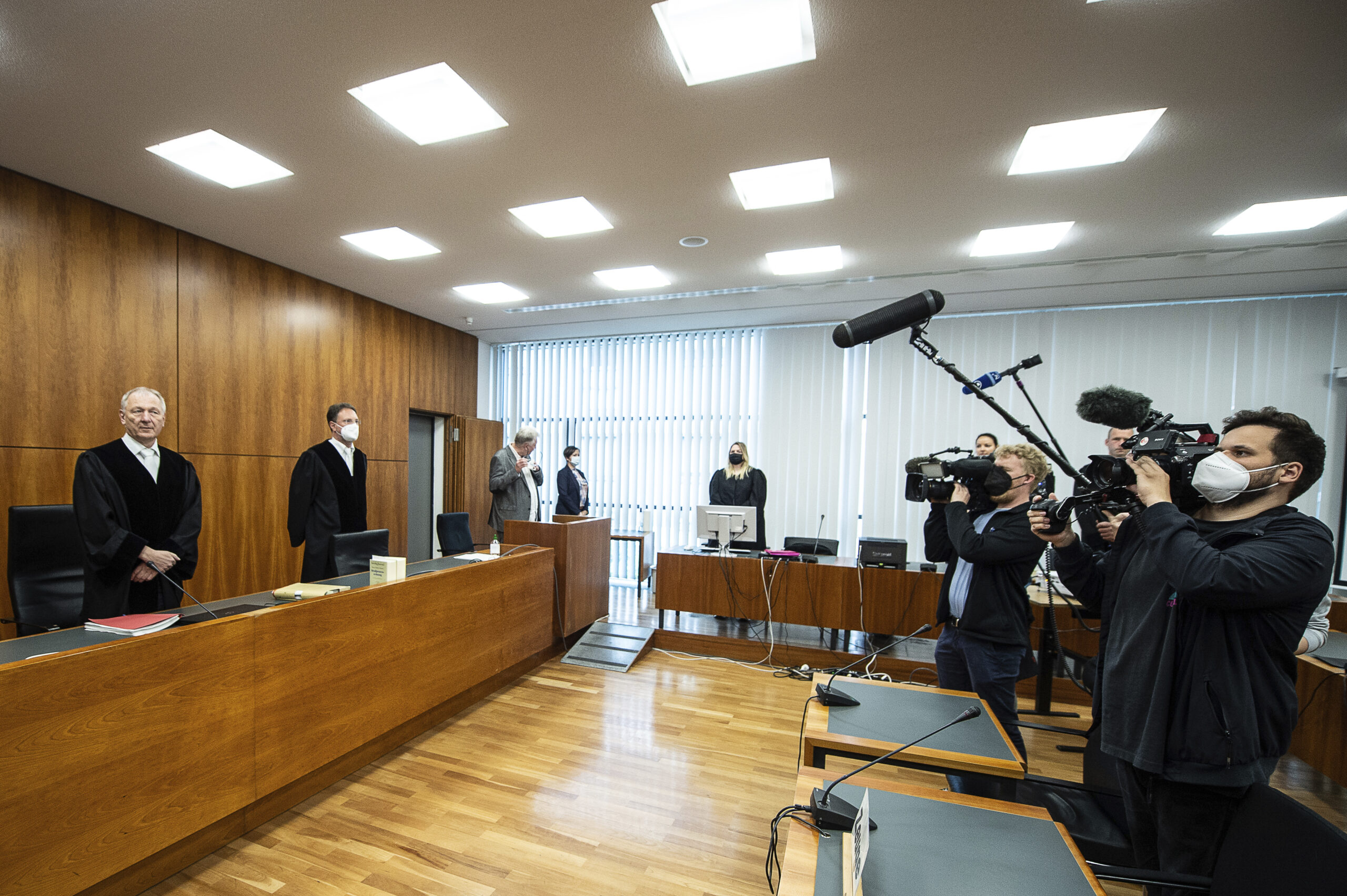 Volker Muetze (l), presiding judge at the Regional Court, stands in the courtroom for the opening in Kassel, HGermany, Wednesday, May 25, 2022. A German court on Wednesday sentenced a woman who posed as a fake doctor and caused the deaths of several of people to life imprisonment for three counts of murder, among other charges. (Swen Pfoertner/dpa via AP)