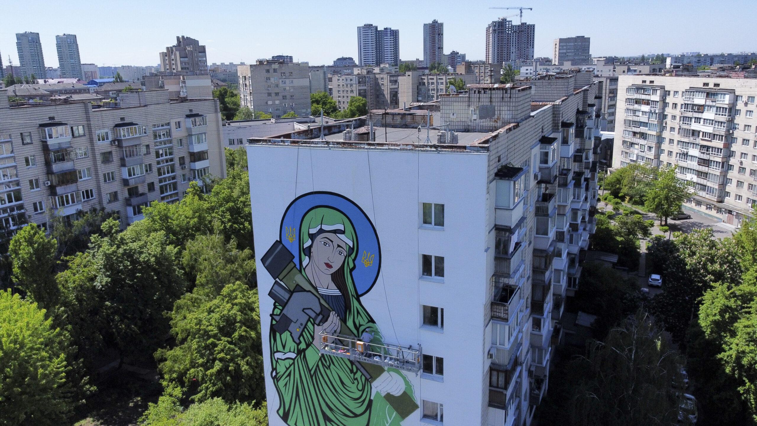 A worker paints a "Saint Javelin", a Virgin Mary holding an American-made anti-tank missile, in Kyiv, Ukraine, Tuesday, May 24, 2022. No matter where they live, the 3-month-old war never seems to be far away for Ukrainians. Those in towns and villages near the front lines hide in basements from constant shelling, struggling to survive with no electricity or gas — and often no running water. But even in regions out of the range of the heavy guns, frequent air raid sirens wail as a constant reminder that a Russian missile can strike at any time — even for those walking their dogs, riding their bicycles and taking their children to parks in cities like Kyiv, Kharkiv, Odesa and Lviv.(AP Photo/Natacha Pisarenko)