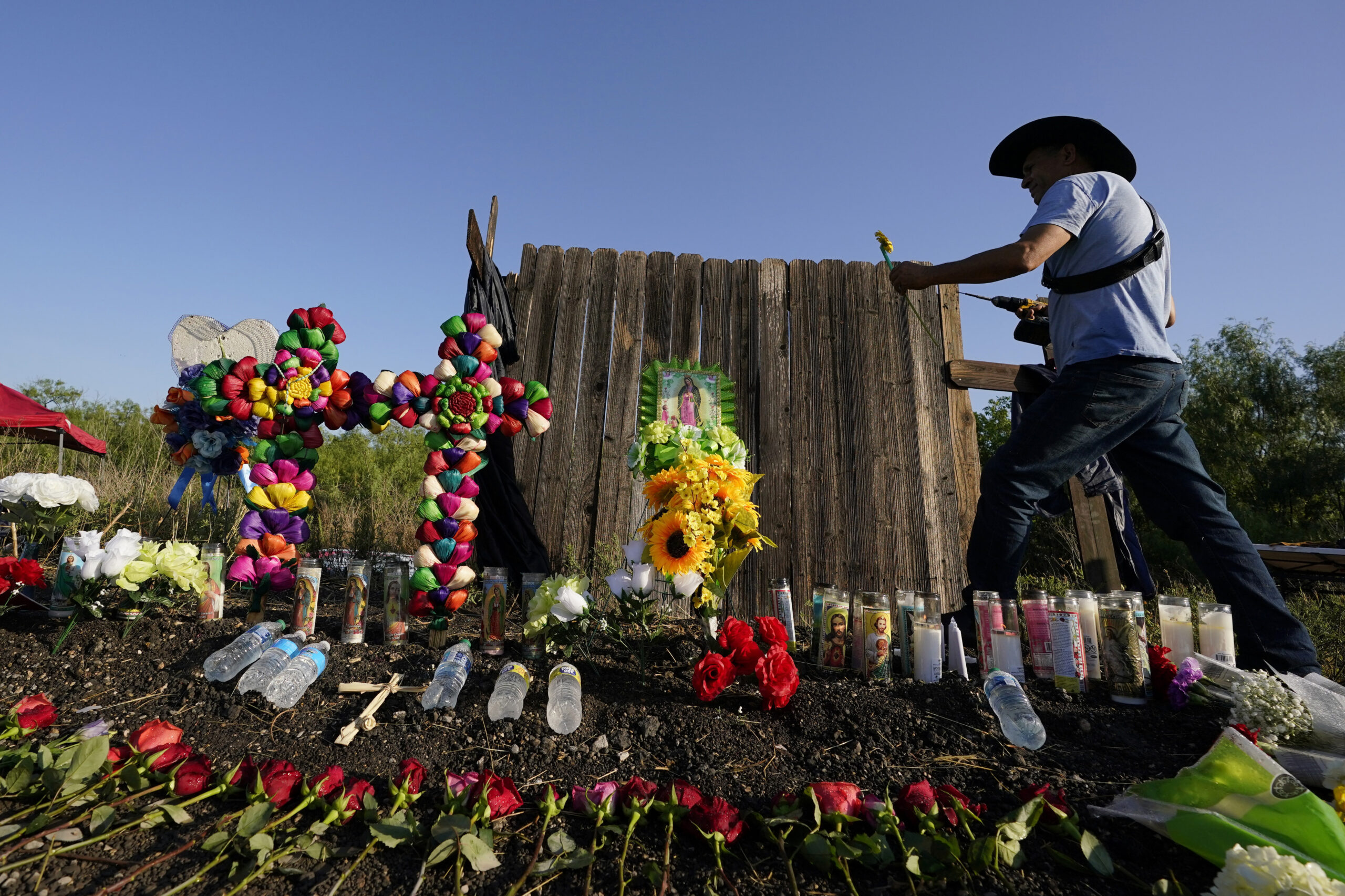 Roberto Marquez of Dallas adds a flower a makeshift memorial at the site where officials found dozens of people dead in an abandoned semitrailer containing suspected migrants, Wednesday, June 29, 2022, in San Antonio. (AP Photo/Eric Gay)