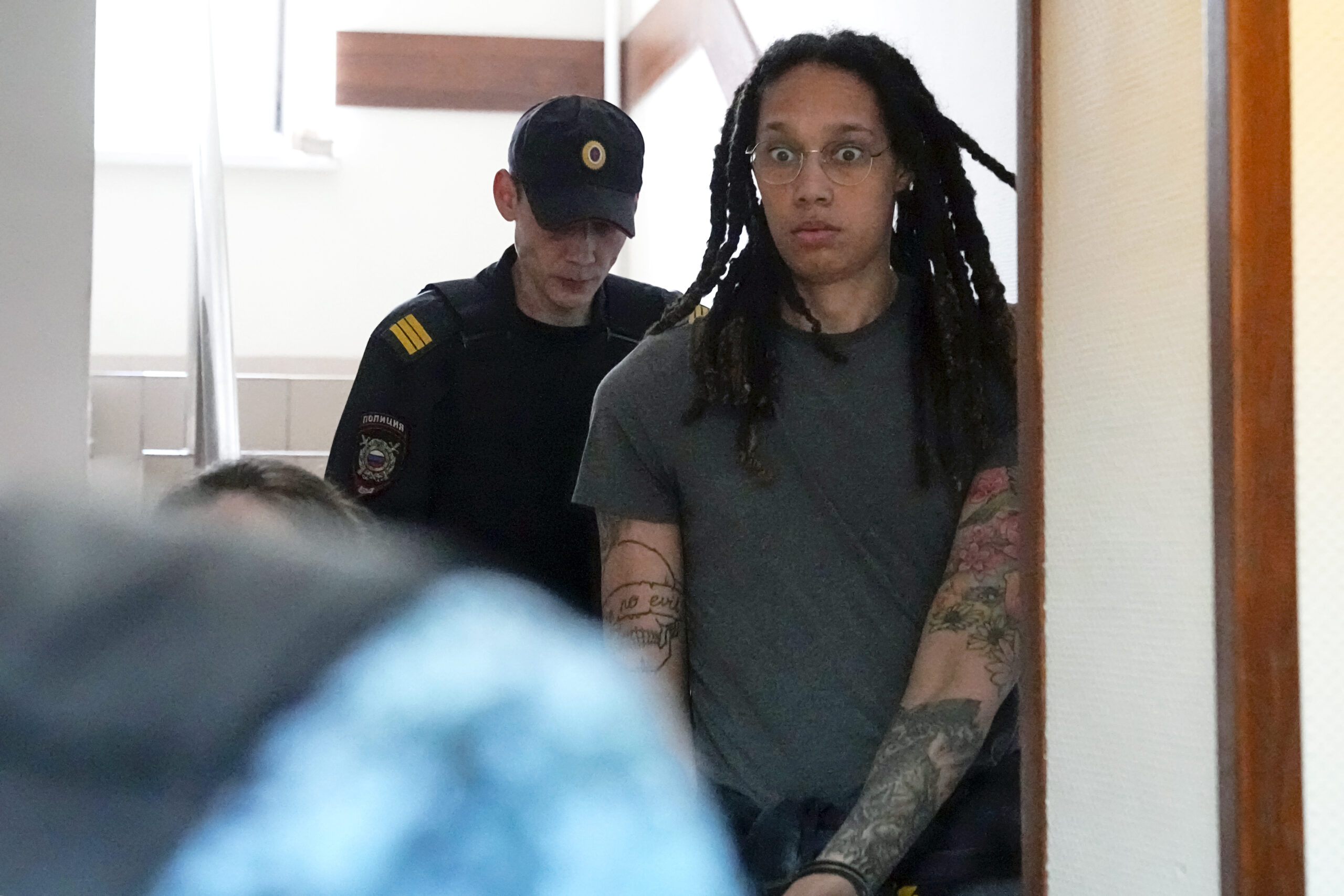 WNBA star and two-time Olympic gold medalist Brittney Griner is escorted to a courtroom for a hearing, in Khimki just outside Moscow, Russia, Monday, June 27, 2022. More than four months after she was arrested at a Moscow airport for cannabis possession, American basketball star Brittney Griner is to appear in court Monday for a preliminary hearing ahead of her trial. (AP Photo/Alexander Zemlianichenko)