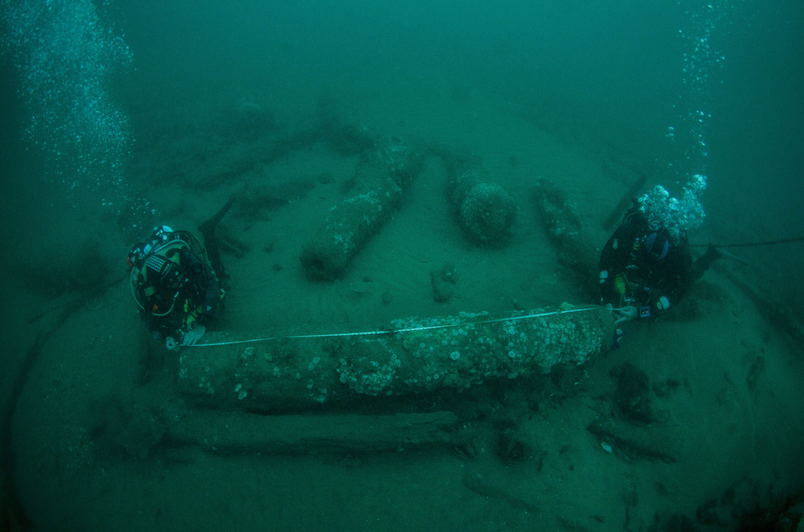 In this undated photo provided by Norfolk Historic Shipwrecks, Julian And Lincoln Barnwell measure the cannon found on the HMS Gloucester in 2007. Excavators and historians are telling the world about the wreck of a royal warship that sank in 1682 while carrying the future king James Stuart. The HMS Gloucester ran aground while navigating sandbanks off the town of Great Yarmouth on the eastern English coast. The wreck of the Gloucester was found in 2007 by brothers Julian and Lincoln Barnwell and others after a four-year search. (Norfolk Historic Shipwrecks via AP)