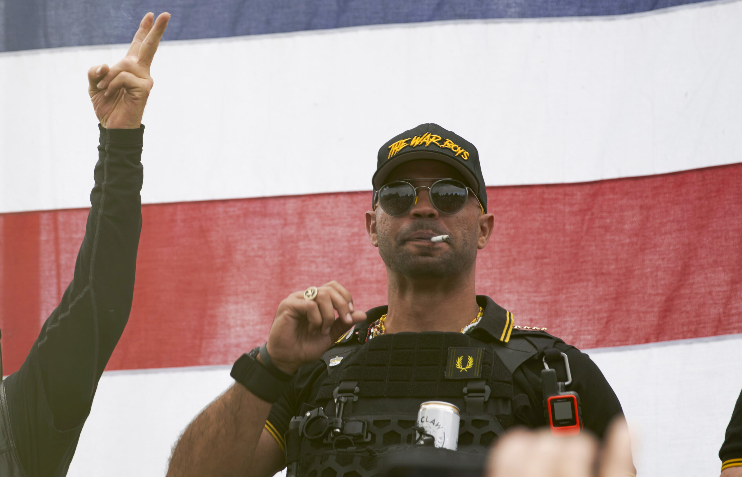 FILE - Proud Boys leader Enrique Tarrio wears a hat that says The War Boys and smokes a cigarette at a rally in Delta Park on Sept. 26, 2020, in Portland, Ore. Tarrio, the former top leader of the far-right Proud Boys extremist group, and other members were indicted Monday, June 6, 2022, on seditious conspiracy charges for what federal prosecutors say was a coordinated attack on the U.S. Capitol to stop Congress from certifying President Joe Biden's 2020 electoral victory.(AP Photo/Allison Dinner, File)