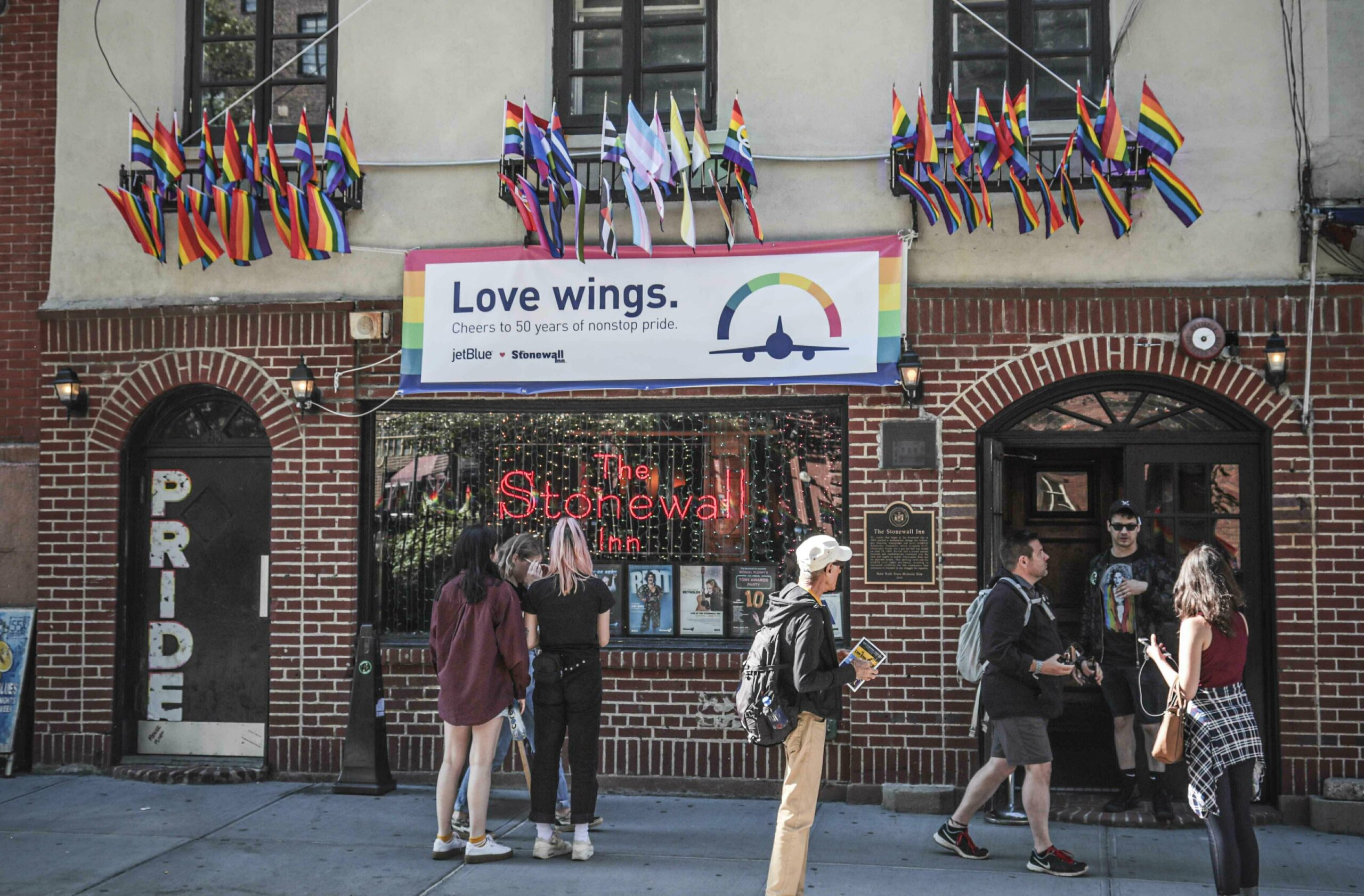 FILE - In this Monday, June 3, 2019, file photo, Pride flags and colors display on the Stonewall Inn bar, marking the site of 1969 riots that followed a police raid of the bar's gay patrons, in New York. A visitor center dedicated to telling the story of LGBTQ rights movement will open next door to the Stonewall Inn. Organizers say the groundbreaking for the Stonewall National Monument Visitor Center in New York City's Greenwich Village neighborhood will take place Friday, June 24, 2022. (AP Photo/Bebeto Matthews, File)