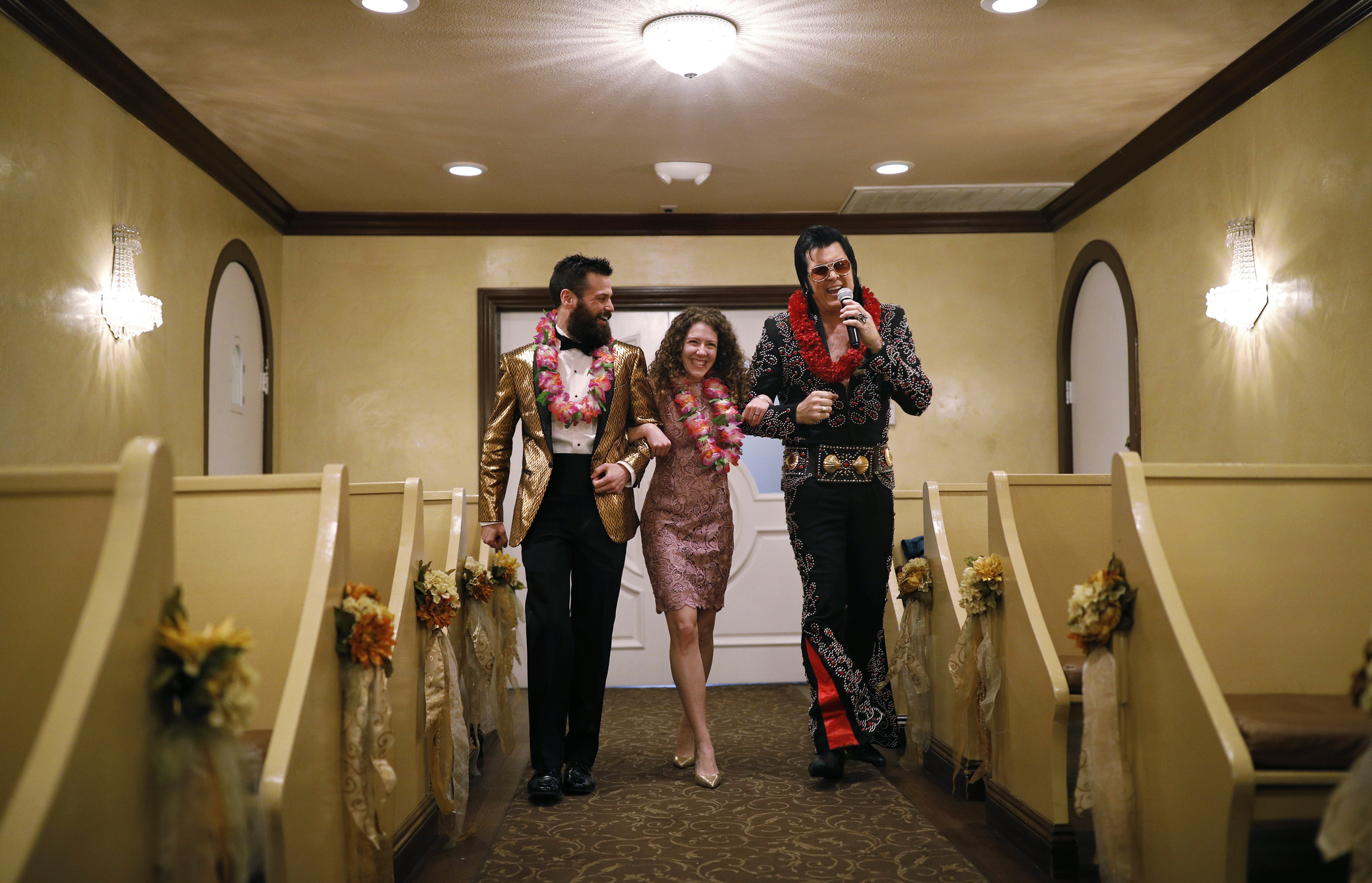 FILE - Elvis impersonator Brendan Paul, right, walks down the aisle during a wedding ceremony for Katie Salvatore, center, and Eric Wheeler at the Graceland Wedding Chapel in Las Vegas. Authentic Brands Group (ABG) sent cease-and-desist letters earlier this month to multiple chapels, saying they had to comply by the end of May, the Las Vegas Review-Journal reported. (AP Photo/John Locher, File)