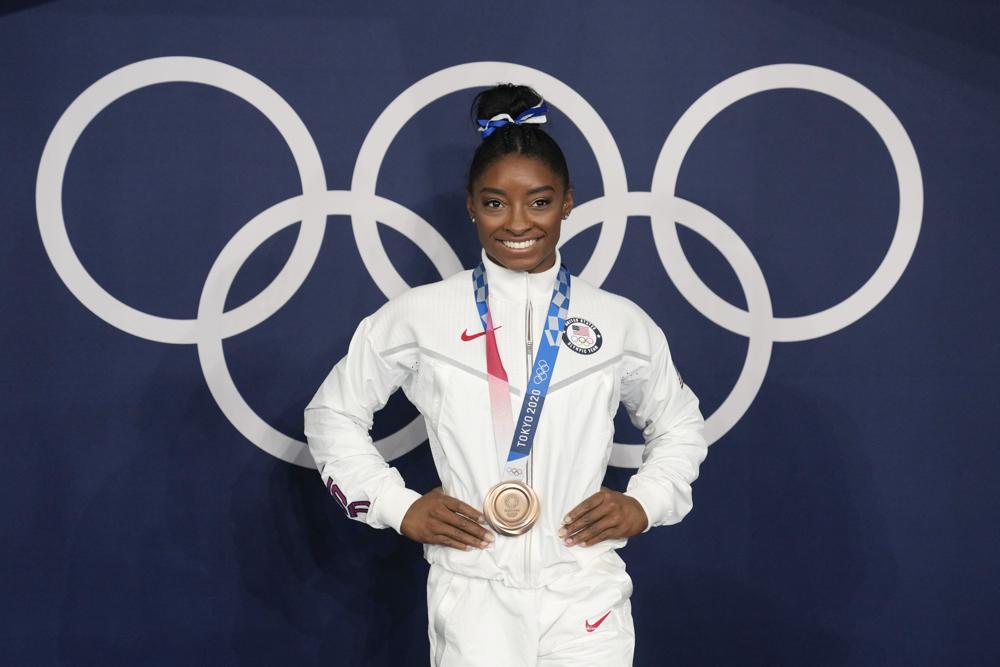 Simone Biles, of the United States, poses wearing her bronze medal from balance beam competition during artistic gymnastics at the 2020 Summer Olympics, Aug. 3, 2021, in Tokyo, Japan.