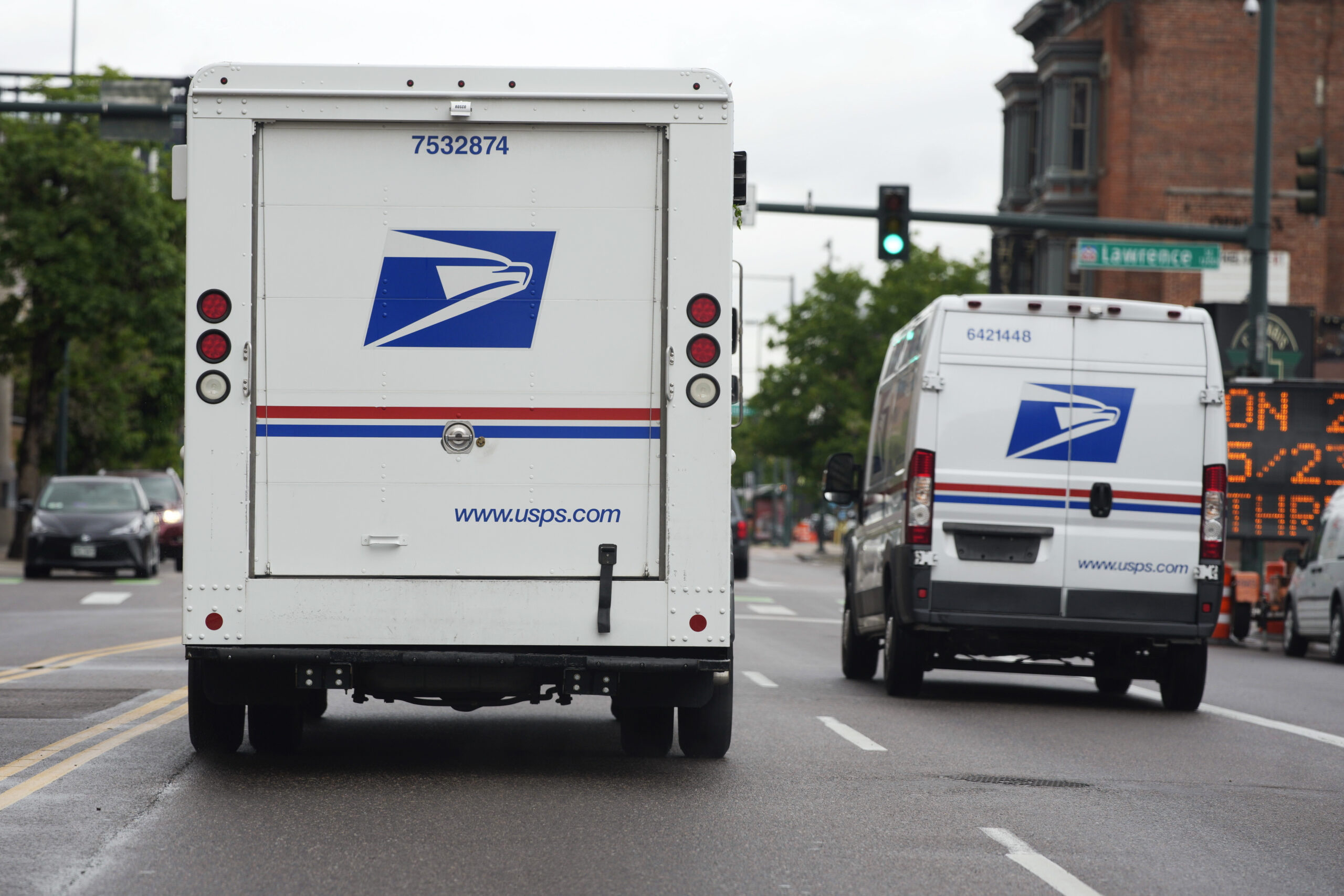 FILE - A USPS logo adorns the back doors of United States Postal Service delivery vehicles as they proceed westbound along 20th Street from Stout Street and the main post office in downtown Denver, Wednesday, June 1, 2022. USPS is creating a division to handle election mail issues as part of an effort to ensure swift and secure delivery of ballots for the 2022 midterm election, officials said Wednesday, July 27, 2022. (AP Photo/David Zalubowski, File)