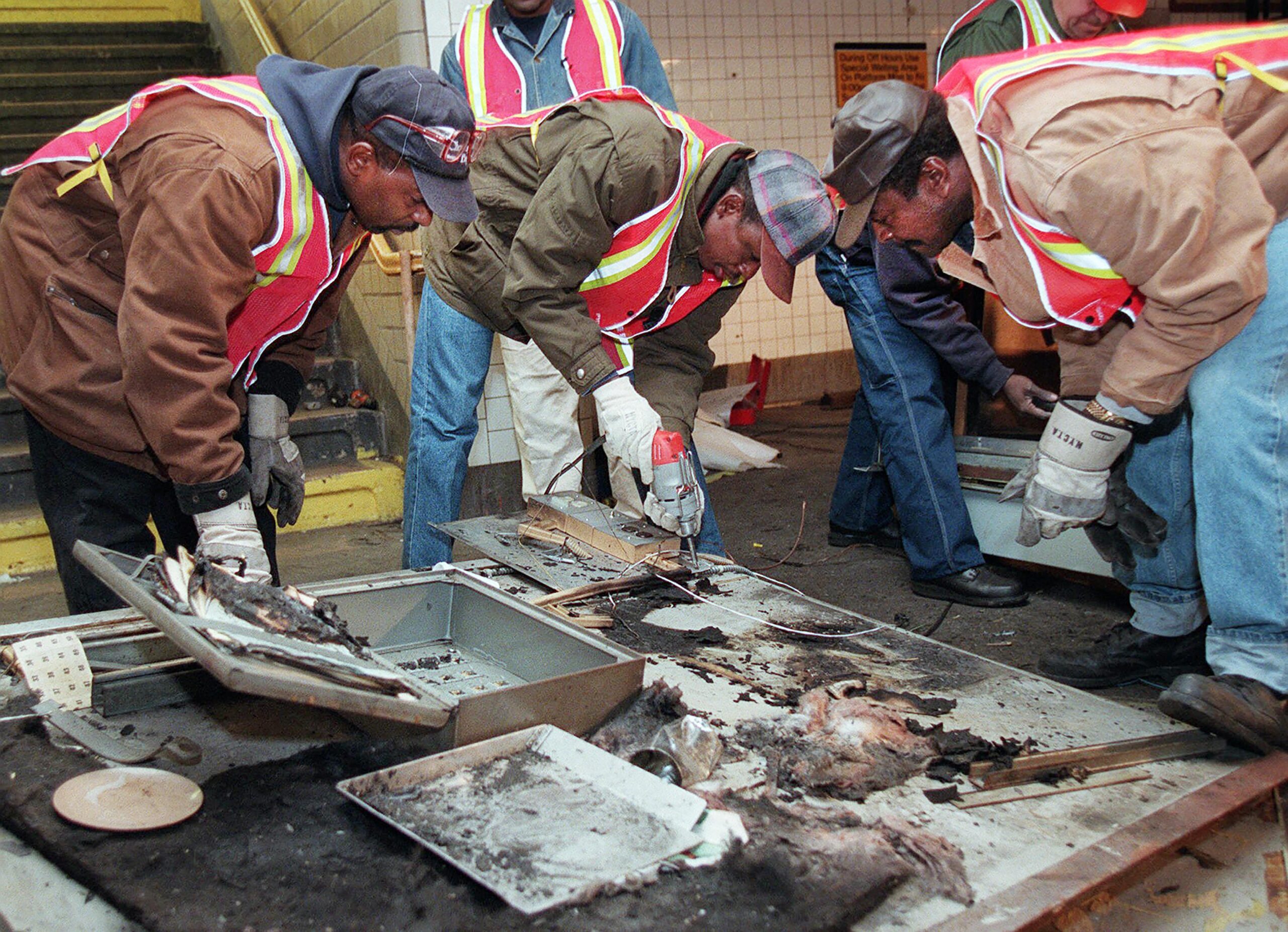 FILE — Transit workers dismantle the charred inner wall of a token booth at the Kingston Avenue and Fulton Street subway station in the Bedford-Stuyvesant section of Brooklyn, Nov. 26, 1995, after attackers sprayed a flammable liquid into the token booth and lit it on fire, according to police. Prosecutors are disavowing the convictions of three men who spent decades in prison for one of the most horrifying crimes of New York's violent 1990s — the killing of a clerk who was set on fire in a subway toll booth. (AP Photo/Rosario Esposito, File)