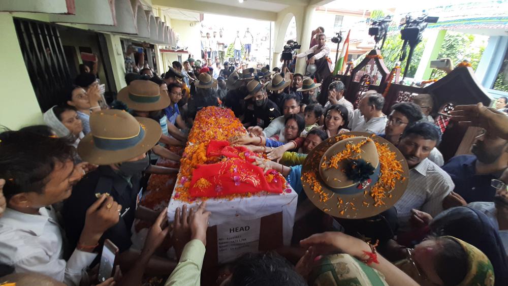 Family members stretch their arms out to touch the coffin containing the remains of Chandra Shekhar, an Indian army soldier who went missing 38 years ago, in Haldwani, India, Wednesday, Aug. 17, 2022.
