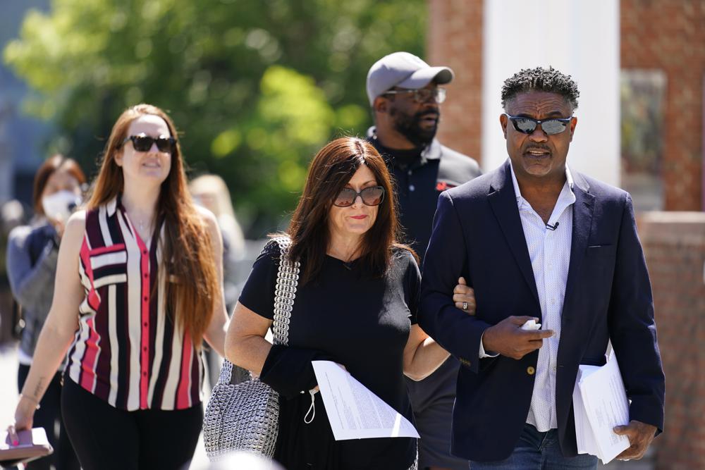 Former NFL players Ken Jenkins, right, and Clarence Vaughn III, center right, along with their wives, Amy Lewis, center, and Brooke Vaughn, left, carry tens of thousands of petitions demanding equal treatment for everyone involved in the settlement of concussion claims against the NFL, to the federal courthouse in Philadelphia on May 14, 2021.