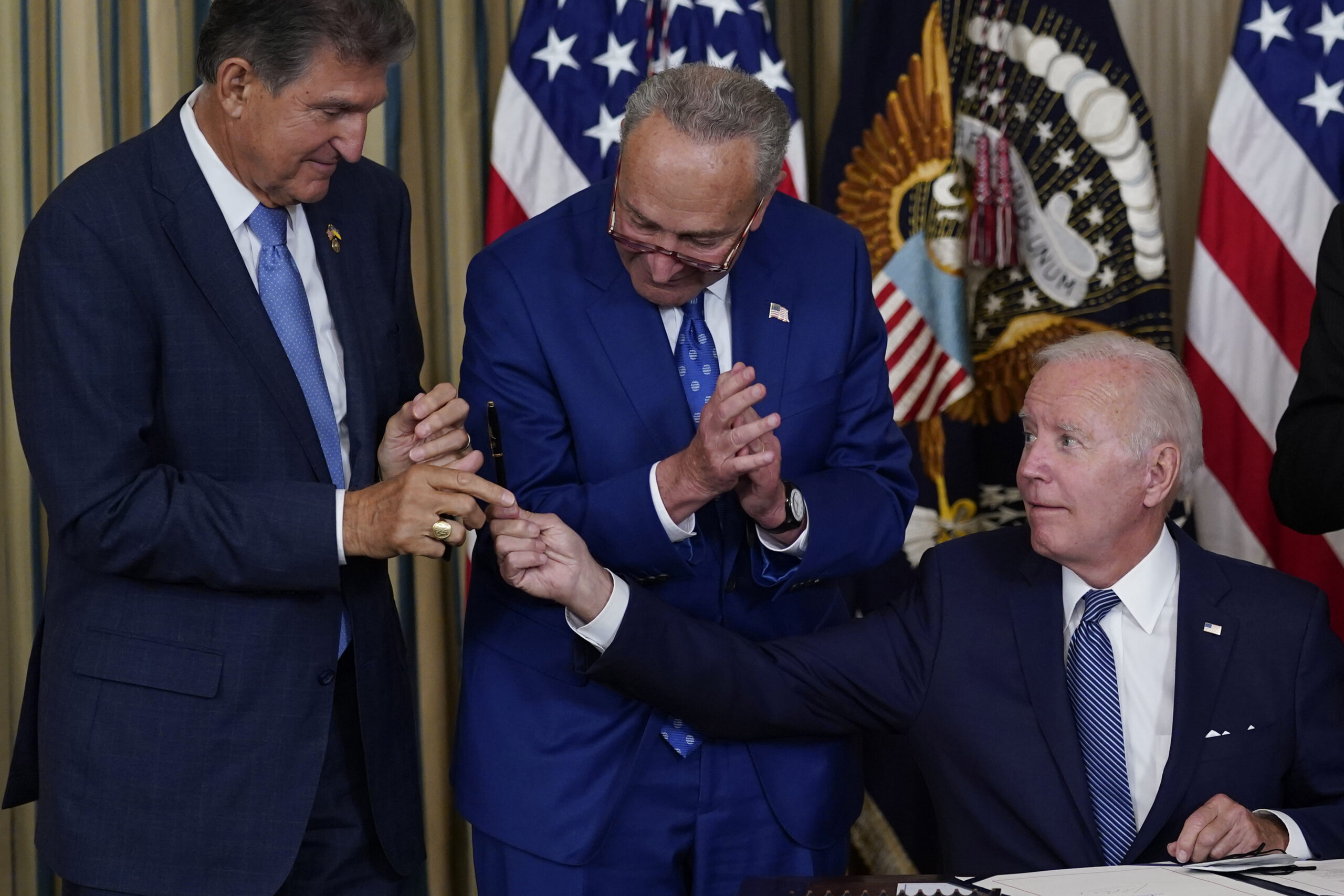 President Joe Biden hands the pen he used to sign the Democrats' landmark climate change and health care bill to Sen. Joe Manchin, D-W.Va., as Senate Majority Leader Chuck Schumer of N.Y., watches in the State Dining Room of the White House in Washington, Tuesday, Aug. 16, 2022. (AP Photo/Susan Walsh)