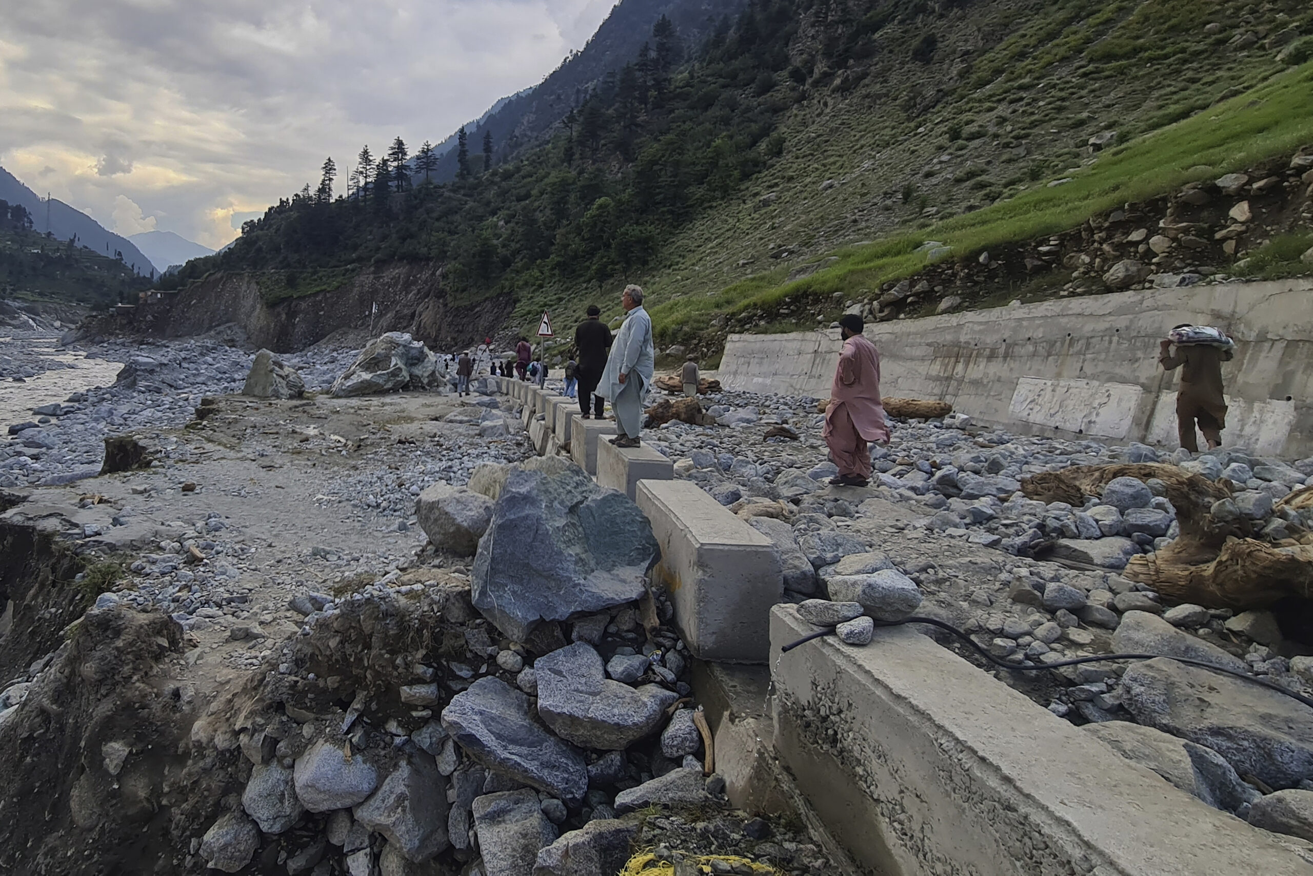 Local residents examine a portion of a road destroyed by floodwaters in the Kalam Valley in northern Pakistan, Tuesday, Aug. 30, 2022. Officials in Pakistan raised concerns Wednesday over the spread of waterborne diseases among thousands of flood victims as flood waters from powerful monsoon rains began to recede in many parts of the country. (AP Photo/Sherin Zada)