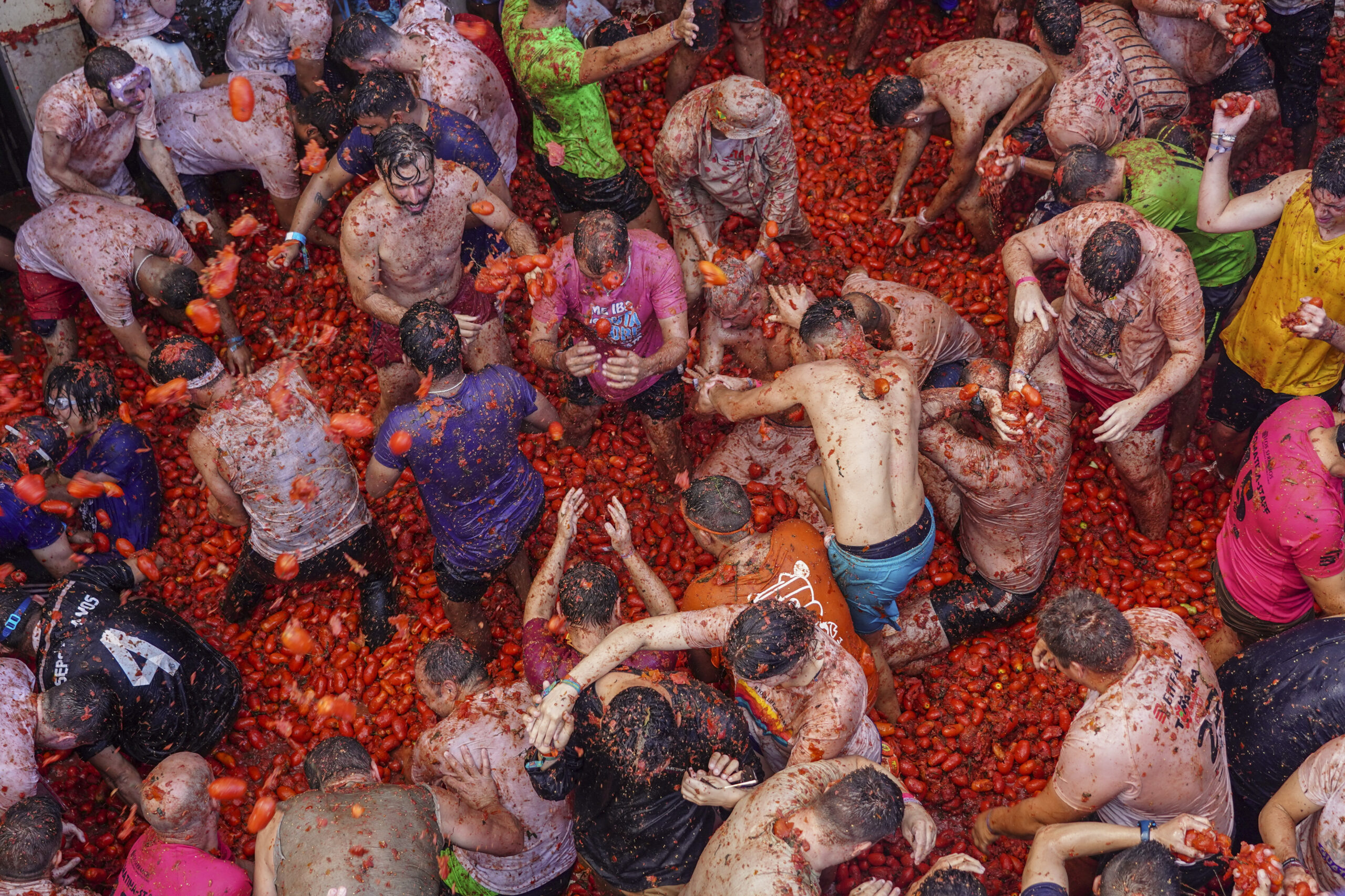 Revellers throw tomatoes at each other during the annual "Tomatina", tomato fight fiesta in the village of Bunol near Valencia, Spain, Wednesday, Aug. 31, 2022. The tomato fight took place once again following a two-year suspension owing to the coronavirus pandemic. (AP Photo/Alberto Saiz)