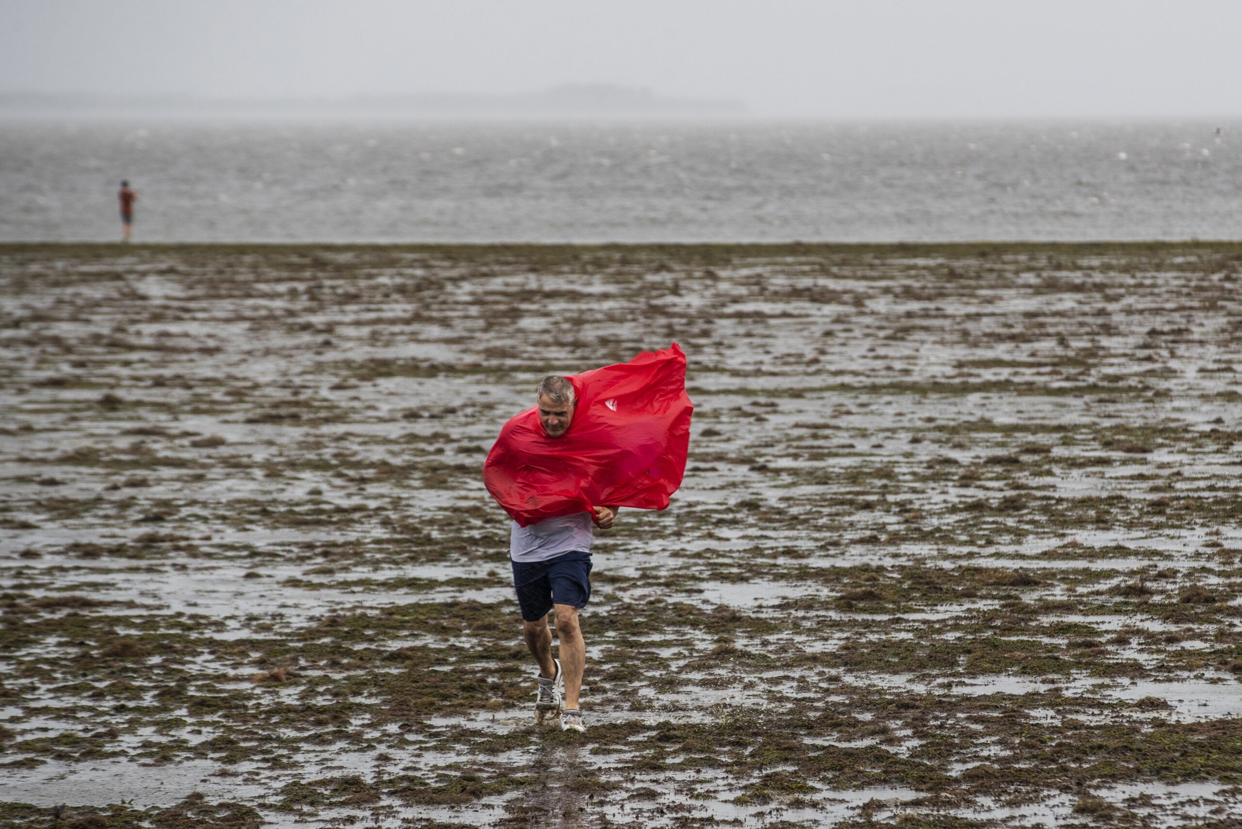 Curious sightseers walk in the receding waters of Tampa Bay due to the low tide and tremendous winds from Hurricane Ian in Tampa, Fla., Wednesday, Sept. 28, 2022. (Willie J. Allen Jr./Orlando Sentinel via AP)